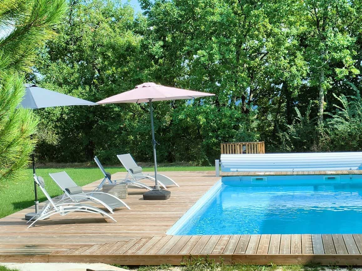Transats et parasol au bord de la piscine chauffée, été en Périgord